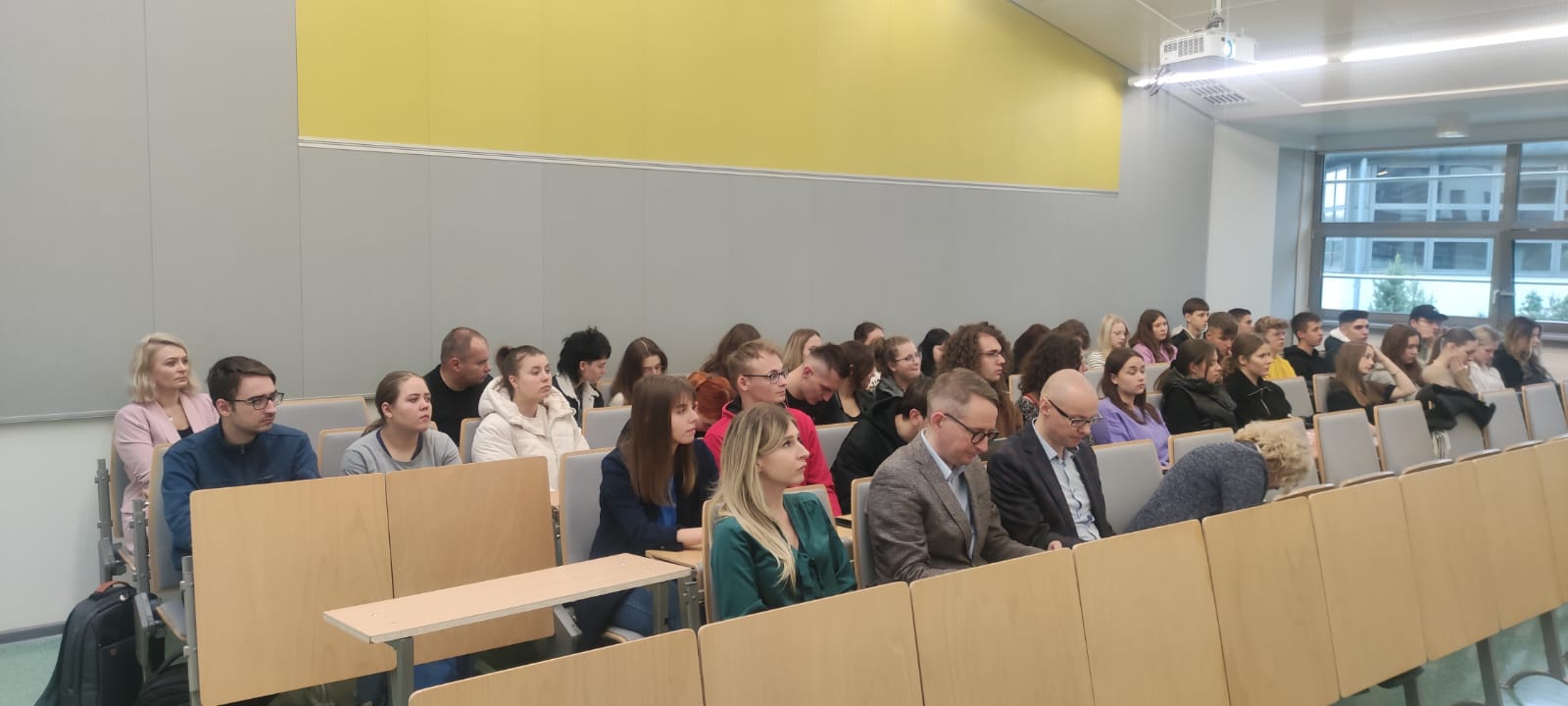 The photo shows listeners of the lecture sitting in the auditorium